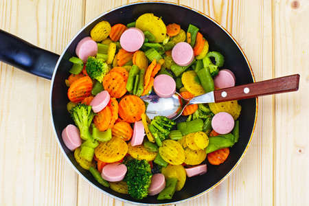 Steamed Vegetables Potatoes, Carrots and Broccoli with Sausages in a Pan Studio Photoの写真素材