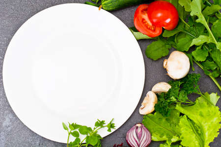Fresh Spring Vegetables, Greens and Empty  Plate with Place for Your Text Studio Photoの写真素材