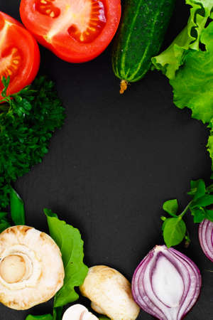 Fresh Spring Vegetables, Greens and Empty Black Plate with Place for Your Text Studio Photoの写真素材