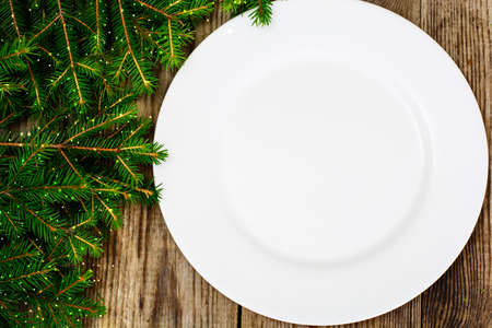 Abstract Christmas and New Year Background with Old Vintage Wooden Boards, Fir Branches, White Empty Plate and Glossy Lights Studio Photoの写真素材