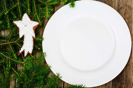Abstract Christmas and New Year Background with Old Vintage Wooden Boards, Fir Branches, White Empty Plate and Glossy Lights Studio Photoの写真素材