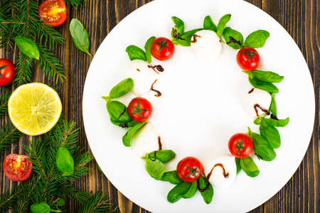 Christmas wreath caprese salad festive appetizer on a white plate. Studio Photo