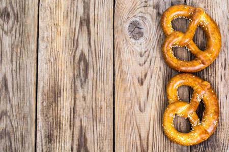 Fresh salty German bread: pretzels on a background of old boardsの写真素材
