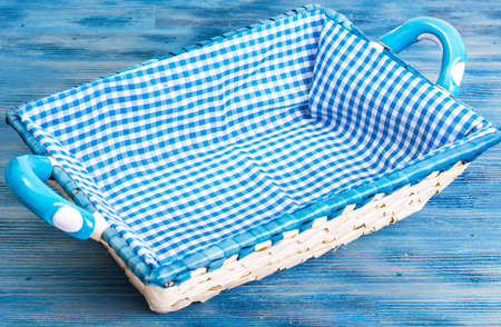 White wicker basket of bread with checkered cloth on blue backgrの写真素材
