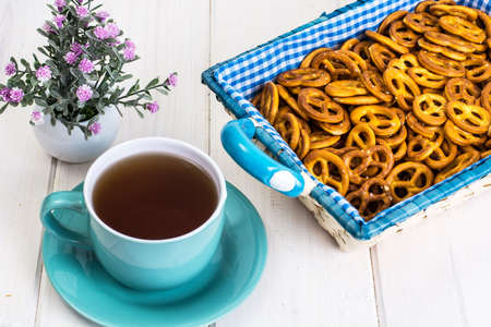 Small salted pretzels cookies in a basket on a white wooden tablの写真素材
