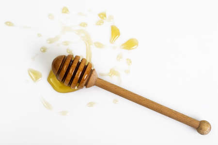 Freshly fragrant honey into a bowl and dipper on white backgrounの写真素材