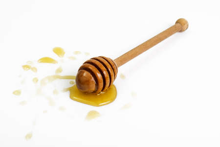 Freshly fragrant honey into a bowl and dipper on white backgroun