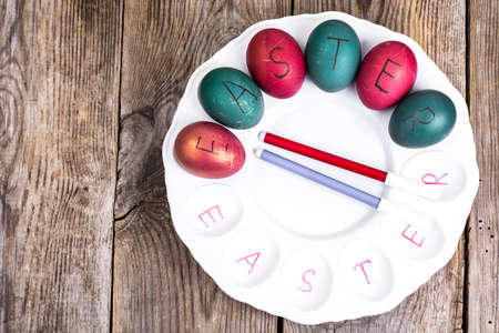 Easter eggs painted on white plate on wooden backgroundの写真素材