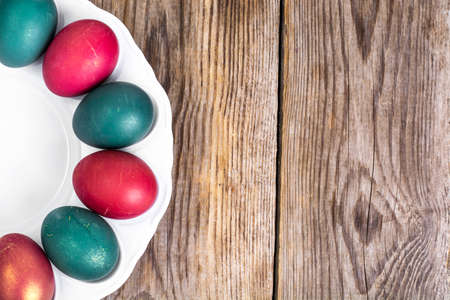 Easter eggs painted on white plate on wooden backgroundの写真素材