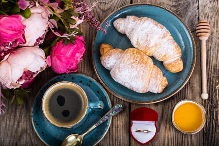 Festive breakfast of espresso, fresh croissant, flowers and giftの写真素材