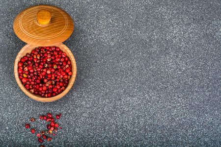 Dried pink pepper peas in a wooden bowl on gray backgroundの写真素材