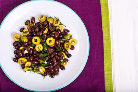 Salad with red beans and green olives in bowl on white boardsの写真素材