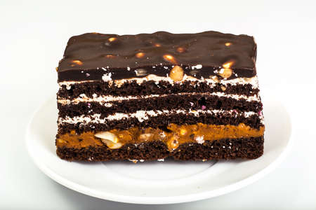 Chocolate caramel cake with nuts and whipped cream on white backの写真素材