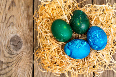 Easter colored eggs, straw, flowersの写真素材