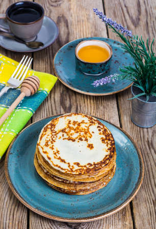 Hot pancakes with honey in vintage bowl on background of an oldの写真素材