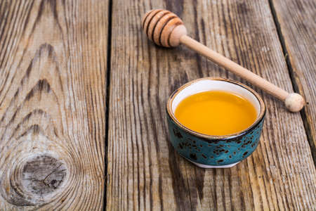 Honey in bowl and spoon on wooden backgroundの写真素材