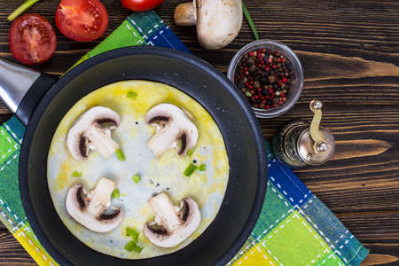 Fried eggs with mushrooms in frying pan