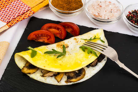 Fried eggs with mushrooms on black stoneの写真素材