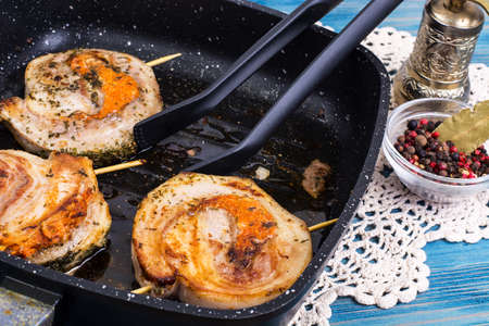 Fried meat on skewers in frying pan, blue background. Studio Photoの写真素材