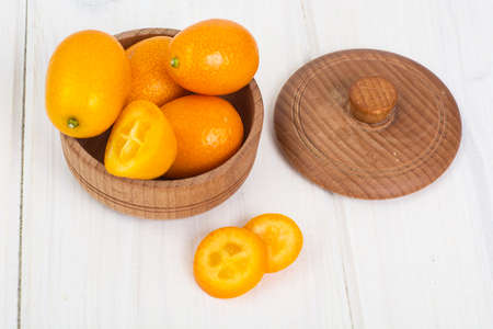 Small ripe orange kumquats on white wooden backgroundの写真素材