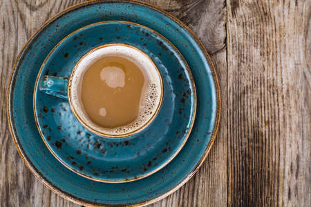 Coffee with milk in blue vintage cup on wooden backgroundの写真素材
