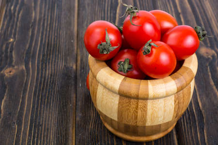 Red tomatoes in wooden salad bowlの写真素材