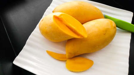 Ripe yellow mango on a black backgroundの写真素材