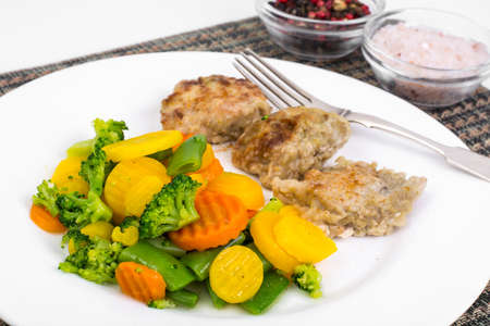 Pieces of fried chicken fillet in batter and mix of stewed veget