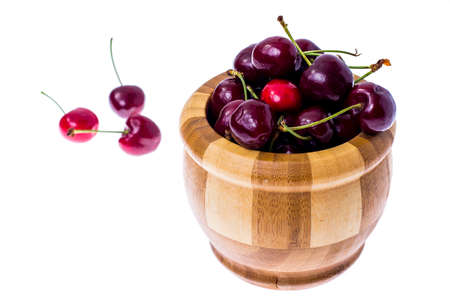 Red ripe juicy cherry in wooden bowl.の写真素材