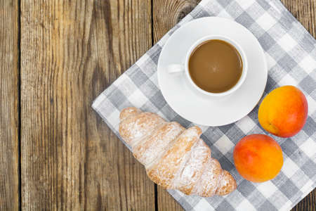 Breakfast. Fresh croissant and cup of coffee with milk on wooden table. Studio Photoの写真素材