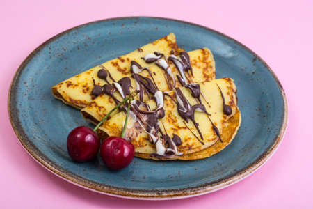 Sweet pancakes with chocolate topping on pastel background. Studio Photo