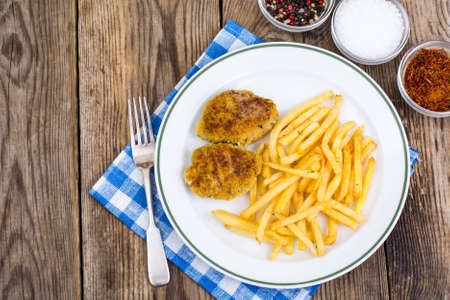 White plate with French fries and meat cutlets on wooden tableの写真素材