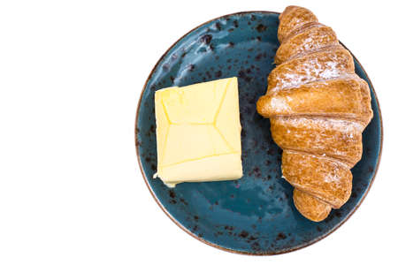 Fresh croissant with butter on blue plate on white backgroundの写真素材