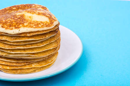 Stack of fresh delicious pancakes on white plate on blue backgroの写真素材