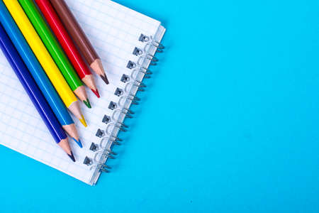 Notepad for notes and colorful pencils on colored background