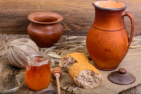Healthy rustic breakfast. Milk in jug and bread on wooden table. Studio Photo