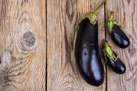 One large and two small eggplant on wooden backgroundの写真素材