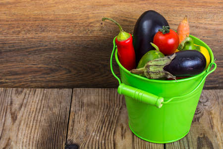 Autumn seasonal vegetables in metal bucket on wooden backgroundの写真素材