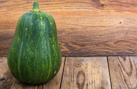 Whole green pumpkin on wooden tableの写真素材