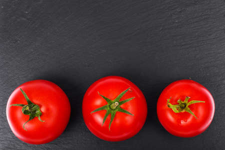 Ripe red tomatoes on black stone plateの写真素材