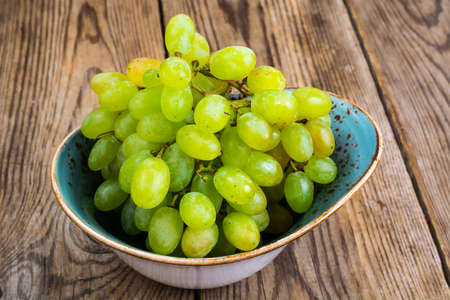 Branch of green grapes on wooden backgroundの写真素材