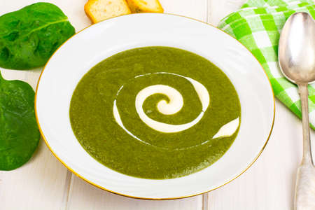 Green cream spinach soup on white wooden tableの写真素材