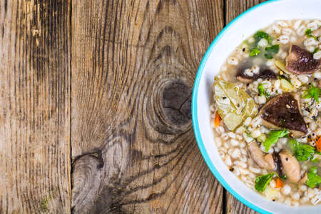 Vegetarian soup with mushrooms and pearl barley for lunch on wooden tableの写真素材