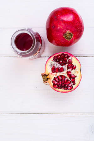 Pomegranate and juice in glass on white wooden backgroundの写真素材