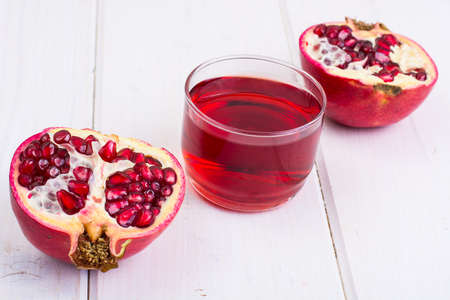Pomegranate and juice in glass on white wooden backgroundの写真素材