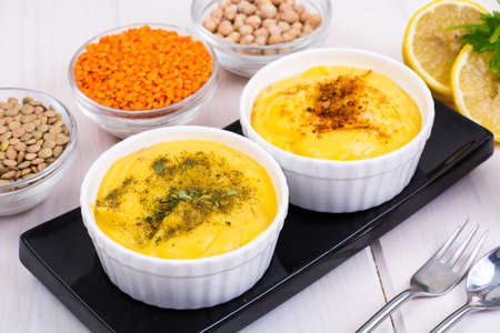 Two bowls with homemade hummus on white wooden backgroundの写真素材