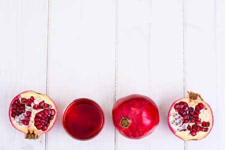 Pomegranate and juice in glass on white wooden backgroundの写真素材