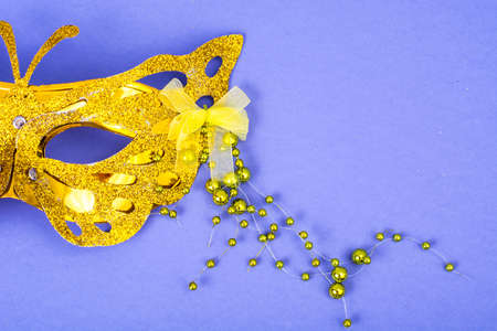 Gold carnival mask with colored beads on violet backgroundの写真素材