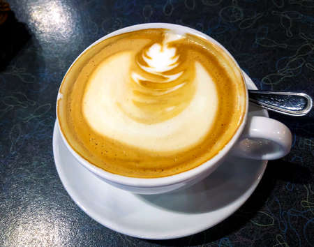 Cappuccino with cinnamon in  white cup on black table