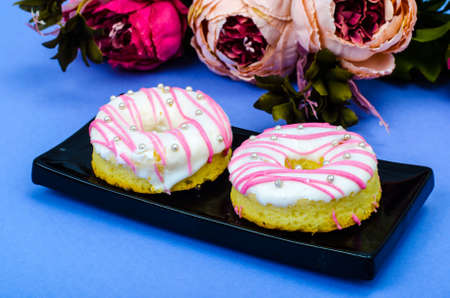 Two fresh round donuts on black plateの写真素材